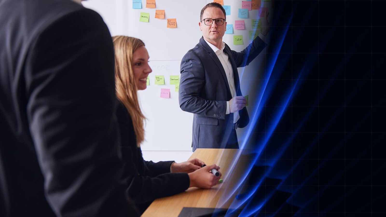 Workshop at ReqPOOL: a consultant explains in front of a wall of sticky notes while two colleagues listen at the table; on the right, the image dissolves into abstract blue shapes.