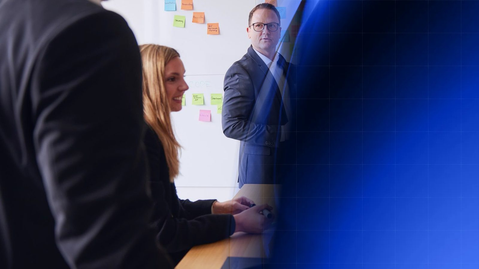 Workshop at ReqPOOL: a consultant explains a wall of colorful sticky notes on processes and systems while a colleague sits at the table with markers and another listens in the foreground; on the right, the image blends into blue geometric shapes.