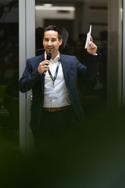 Host with a microphone in a glass door holding up a sheet of paper