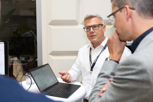 Guest explaining something to another guest at a standing table with a laptop