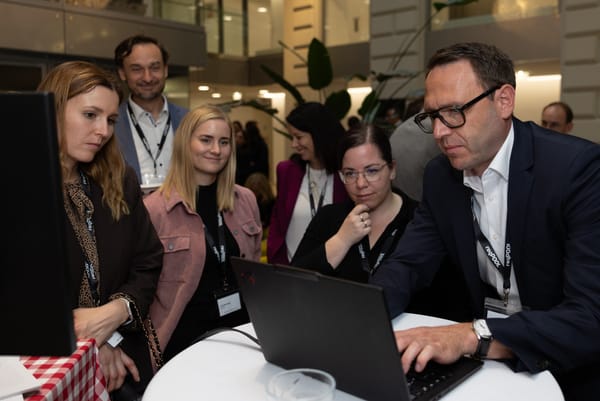 Several guests standing around a laptop while a man types intently