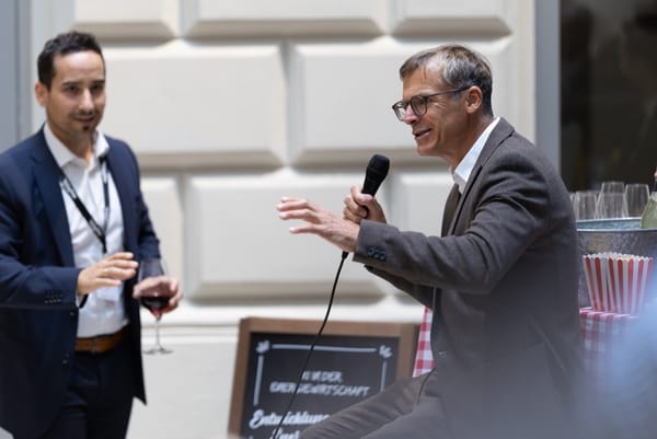 Two men talking, one gesturing with a microphone in hand