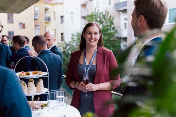Smiling guest with a glass in front of a tiered stand of canapés on the terrace