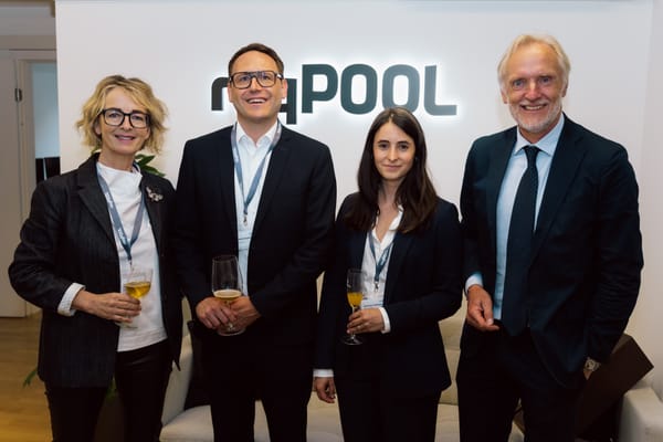 Four people smiling in front of the ReqPOOL logo on the wall