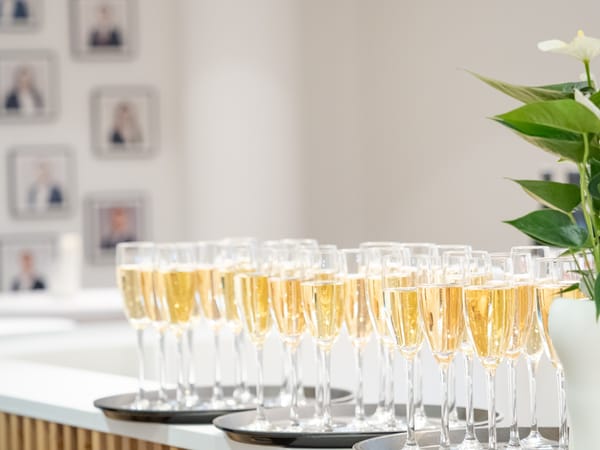 Filled champagne glasses on trays, with the office portrait wall in the background