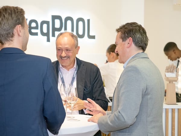 Three guests chatting at a standing table in front of the ReqPOOL lettering