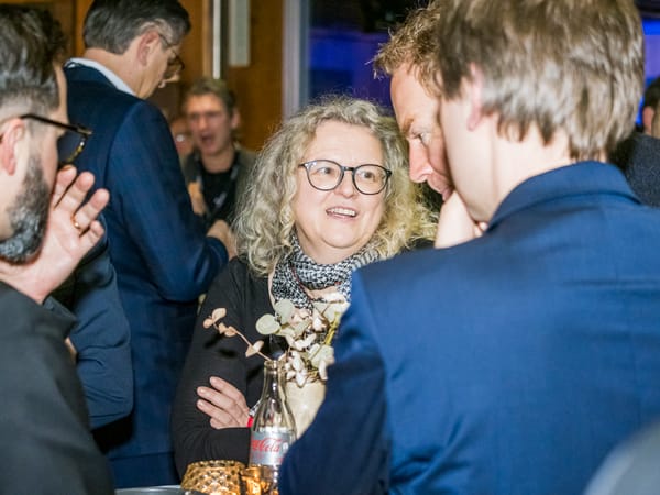 Gästin mit Brille im Gespräch mit zwei Männern