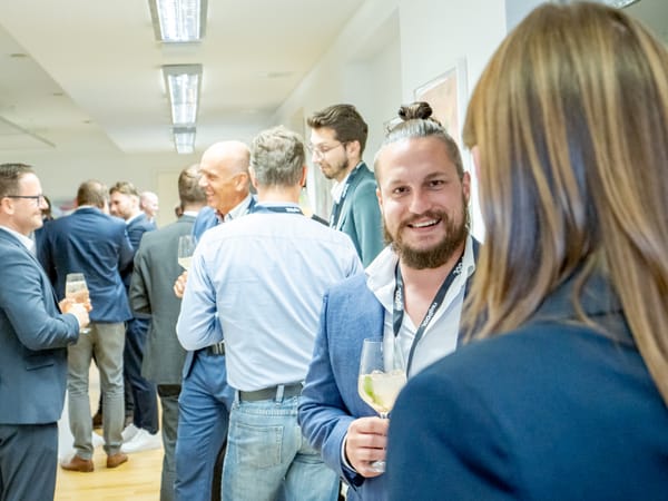 Guests with drinks in conversation in the crowded event room