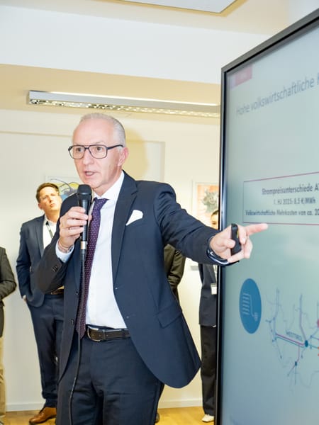 Speaker with a microphone in front of a slide on electricity price differences
