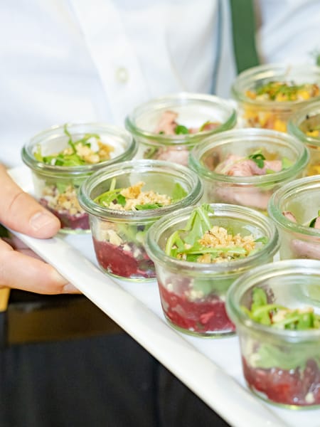 Waiter carrying a tray of salads in small glass jars