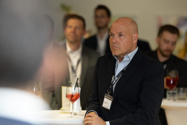 Aufmerksamer Gast mit Cocktail an einem Stehtisch hört zu