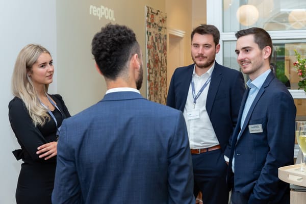 Four people talking in the ReqPOOL office