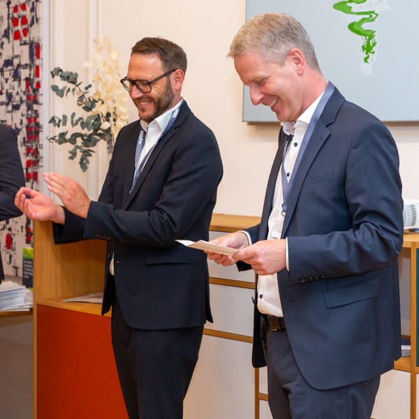 Two guests laughing over a sheet of paper at the reception desk
