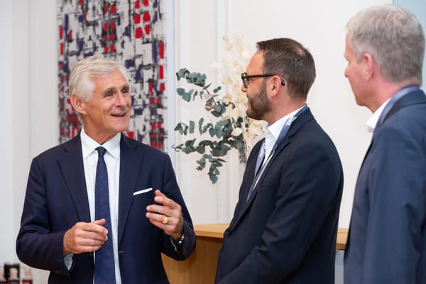 Three guests talking in front of a patterned wall