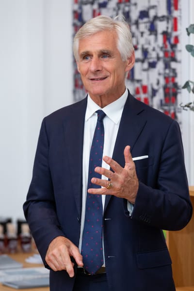 Guest in a suit speaking animatedly with a hand gesture
